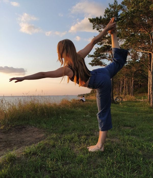 A person in a flowing yoga pose outdoors during sunset.